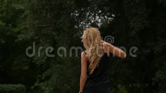 自然背景下金发女人的背景美丽的女孩摆着飞舞的头发慢动作视频的预览图