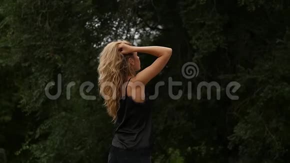 自然背景下金发女人的背景美丽的女孩摆着飞舞的头发慢动作视频的预览图