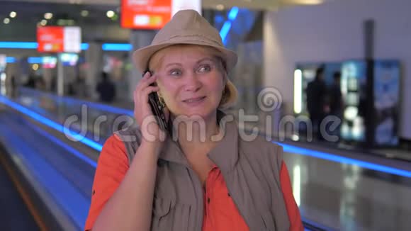 一个女人在机场坐着一台移动的自动扶梯在打电话视频的预览图