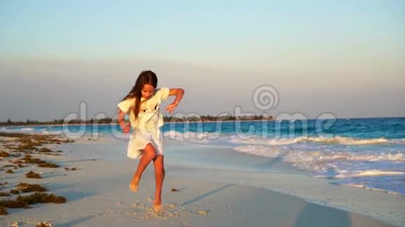 可爱的快乐小女孩在白色海滩日落可爱的孩子在热带海滨慢动作视频舞蹈视频的预览图