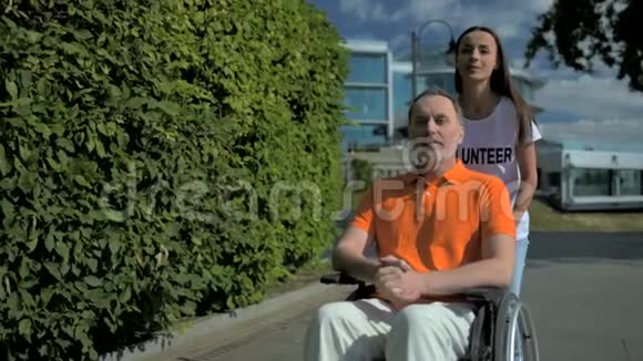 积极的女性志愿者推着轮椅的男人视频的预览图