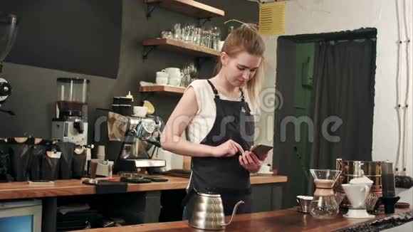 活泼开朗的女咖啡师在咖啡店用手机发短信视频的预览图