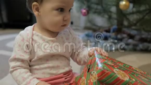 可爱的女婴在圣诞树附近打开礼物视频的预览图