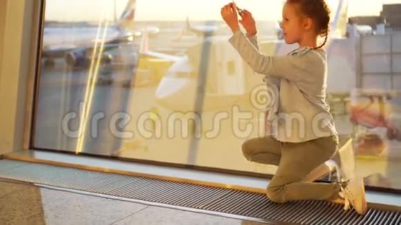 可爱的小女孩在机场玩小模型飞机等待登机飞行和飞机的概念视频的预览图