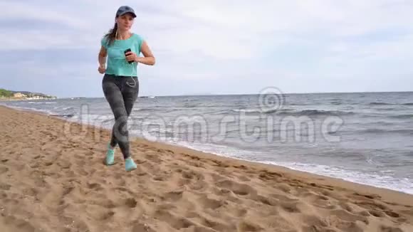 运动的女人沿着海滩奔跑不同速度的视频正常和缓慢视频的预览图