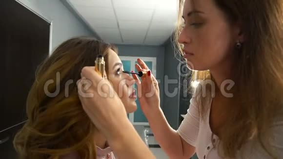 化妆师在一个年轻的女人身上做化妆睫毛视频的预览图