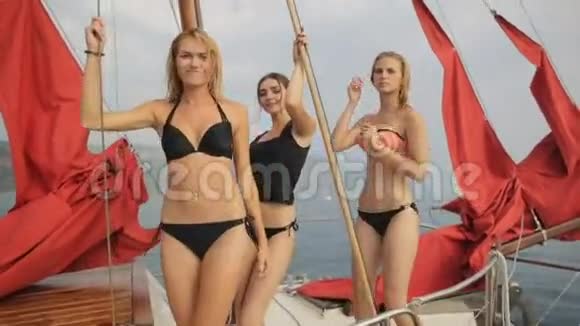 穿着比基尼的年轻美女在一艘红帆的游艇甲板上翩翩起舞视频的预览图