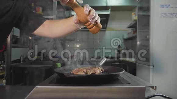 肉在烤锅上煎厨师在烹饪牛排中倒入香料慢动作视频的预览图