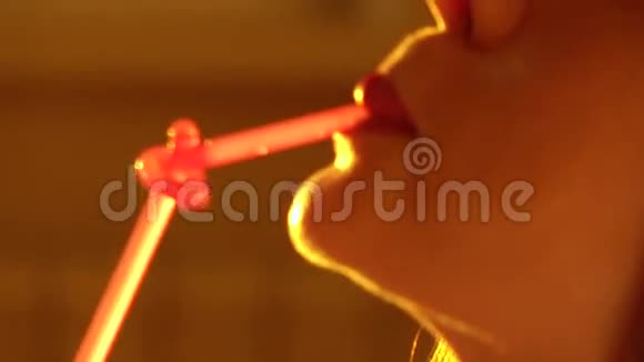 漂亮的女人用粉红色的吸管喝酒4K型特写镜头视频的预览图