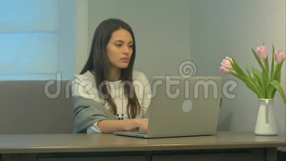 年轻漂亮的女人在家里沙发上用现代笔记本电脑工作视频的预览图