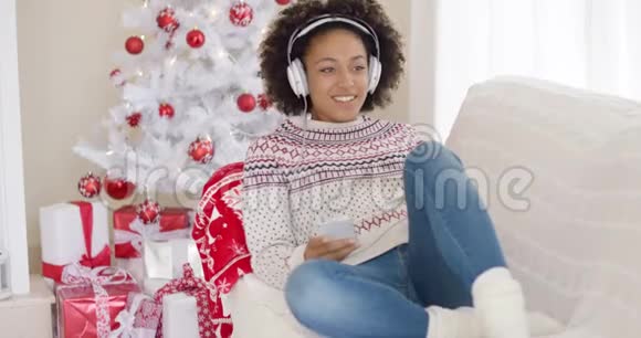 年轻女孩放松地听圣诞音乐视频的预览图