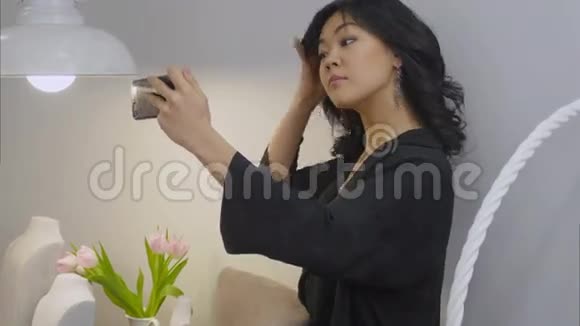 戴着新珠宝的亚洲黑发女人用手机自拍视频的预览图