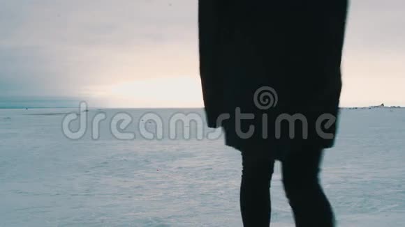 穿着黑色衣服走在冰雪覆盖的平原上的女孩剪影视频的预览图