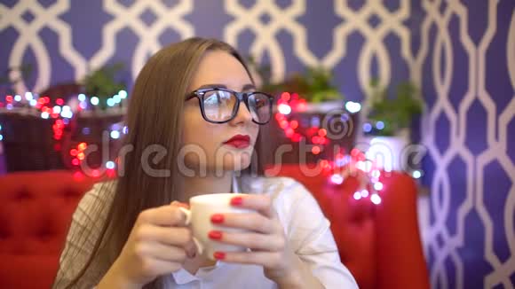 坐在咖啡馆喝咖啡的年轻女子慢动作视频的预览图