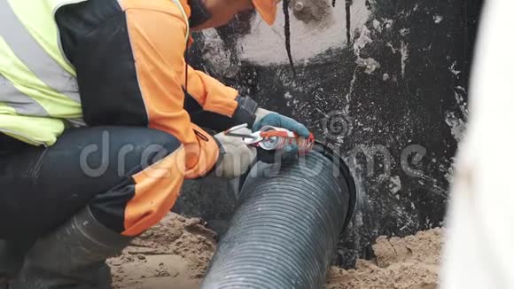 工人在带肋的塑料管与混凝土孔之间缝上密封胶视频的预览图
