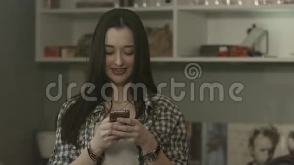 美丽的快乐女孩看着她的手机微笑视频的预览图