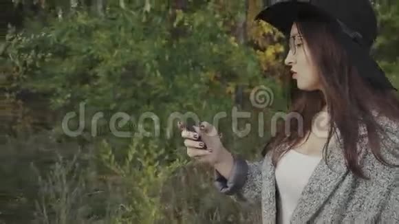 戴着黑帽子戴着眼镜的年轻漂亮女人在户外给男朋友打短信视频的预览图