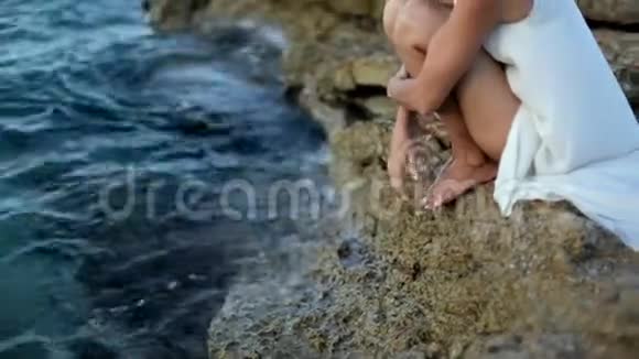 穿着白色连衣裙的漂亮女孩坐在海滩上希腊视频的预览图