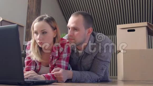 搬家家庭技术和夫妇概念微笑夫妇与笔记本电脑坐在地板上的新房子视频的预览图