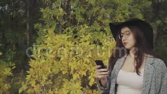 戴着黑帽子戴着眼镜的年轻漂亮女人在户外给男朋友打短信视频的预览图