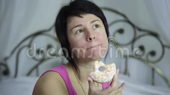 女人在床上吃甜甜圈早餐和垃圾食品视频的预览图