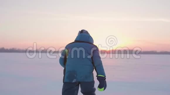 一个孩子在冬天户外玩耍跑步把雪扔到顶部美丽的日落户外运动视频的预览图