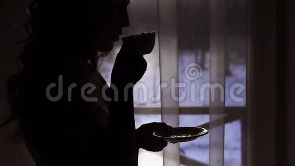 在4k窗口附近喝一杯饮料的女人的夜晚轮廓视频的预览图