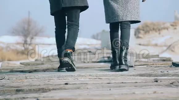 年轻漂亮的夫妇穿着外套走在木板桥上绕着雪视频的预览图