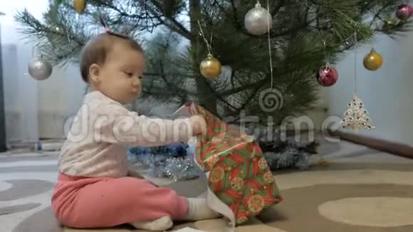 可爱的女婴在圣诞树附近打开礼物视频的预览图