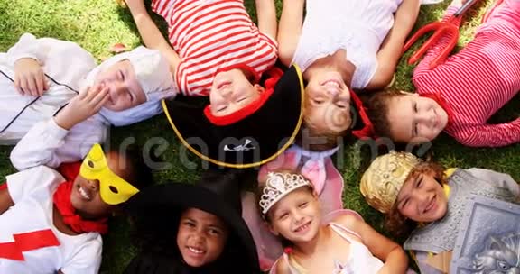 一群穿着各种服装躺在草地上的孩子视频的预览图