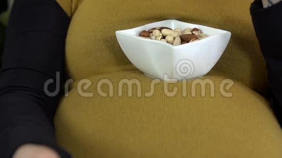 母亲吃坚果的详细照片是从她的腹部顶部的杯子视频的预览图