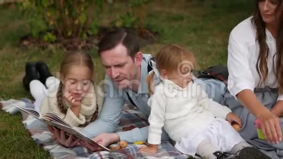 快乐的一家人坐在草地上夏天在草坪上休息慢动作视频的预览图