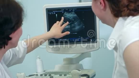 妇科医生和孕妇看显示胎儿的超声波检查视频的预览图