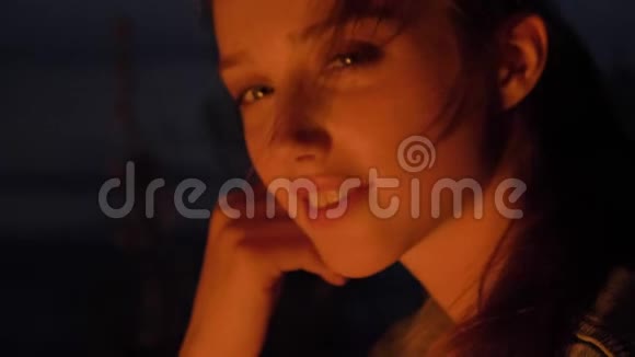 年轻的白种人女孩坐在大自然的炉火旁看着镜头画像视频的预览图