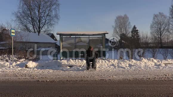冬天坐轮椅等公共汽车的残疾人视频的预览图