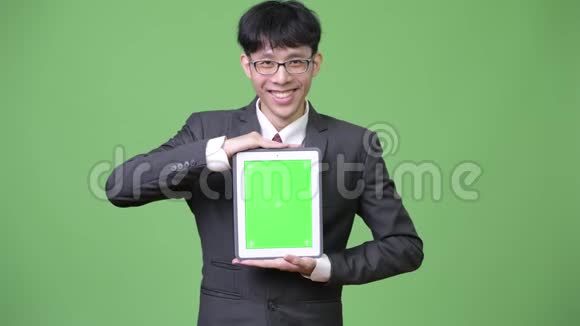 年轻快乐的亚洲商人展示数码平板电脑视频的预览图