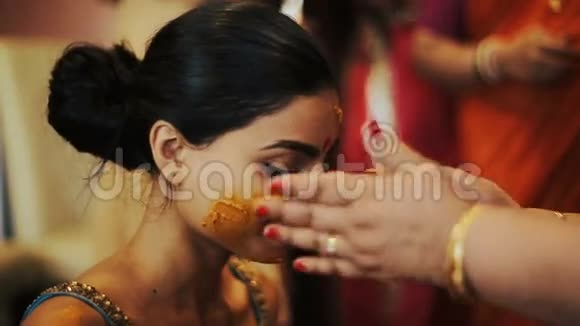 女人的手抚摸着印度新娘的脸脸上沾满了姜黄膏视频的预览图
