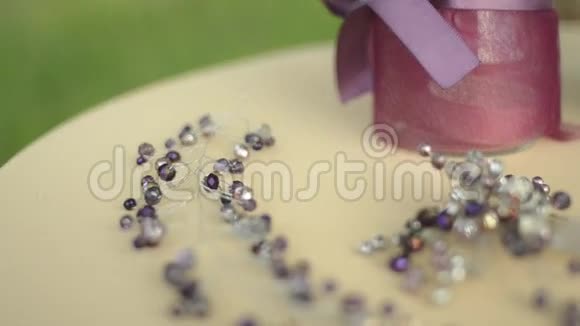 餐桌上的婚礼配饰紫色的花米色的织物胸针或梳子在头发上为新娘可变焦点视频的预览图