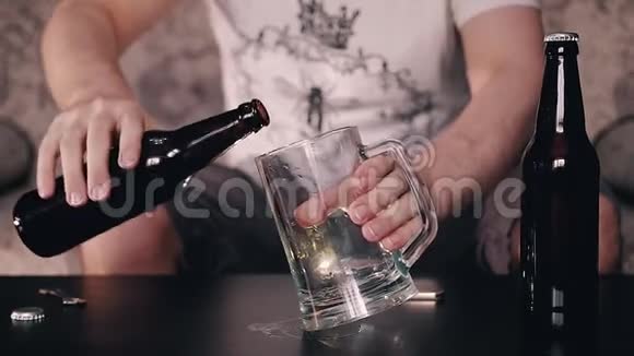 一个人把一瓶漂亮的蜂蜜色的啤酒倒进一个大啤酒杯里视频的预览图