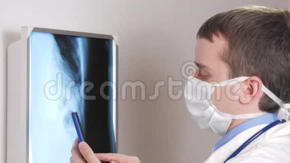一位戴面膜的年轻医生在诊所里用电话一名男子记录了一名病人x线的结果视频的预览图