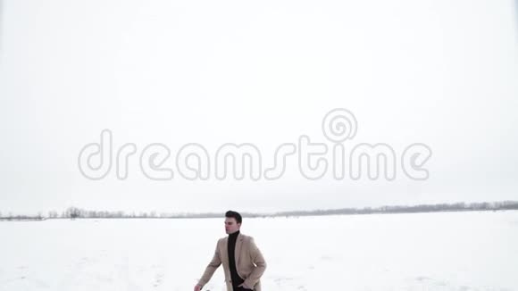 年轻的富商走在雪地上骑着红肌肉车视频的预览图