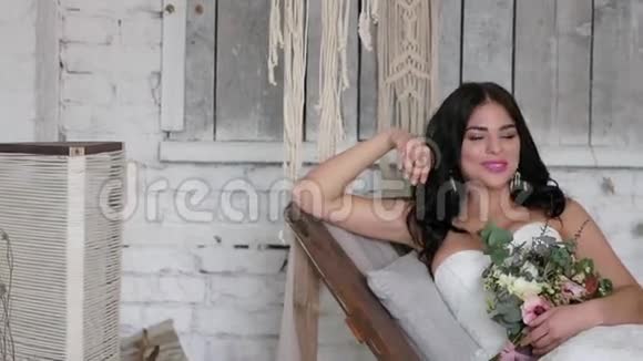 新娘是一个美丽的黑发女人躺在沙发上在一个美丽的内部风格的波霍视频的预览图