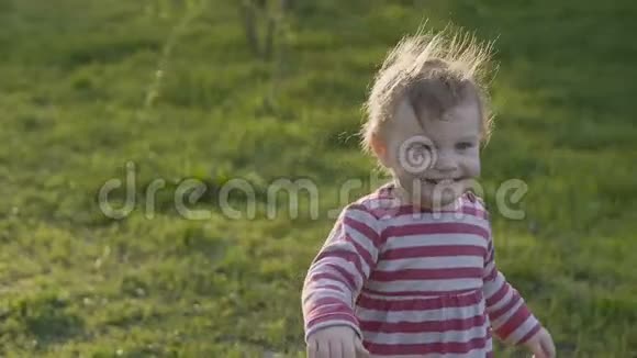 快乐的小女孩走在草地上走向妈妈带着一颗古老的心在春天的公园里视频的预览图