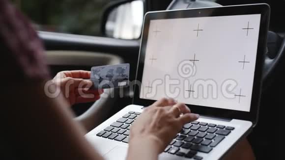 女人在车里用一张带笔记本电脑的信用卡付款视频的预览图
