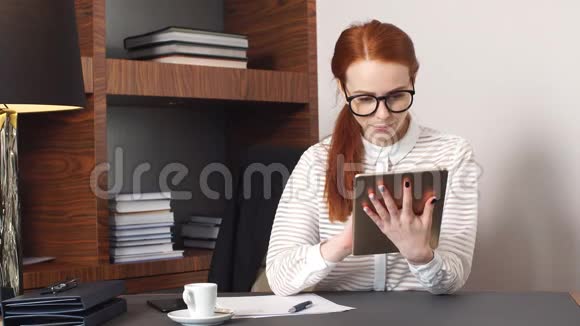 年轻成功的女商人在家庭客厅家庭办公室使用平板电脑视频的预览图