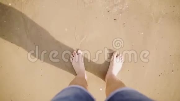 在海边沙滩上晒黑的白种人的腿高高的视野穿牛仔裤的人光着脚走视频的预览图