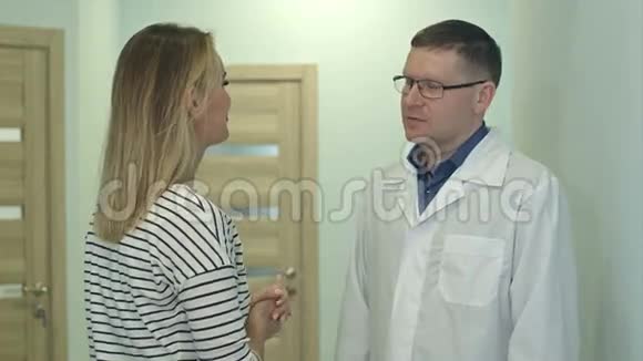 男医生在医院大厅里与年轻女子交谈视频的预览图