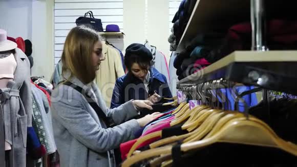 两个女朋友微笑着选择商店里的衣服视频的预览图