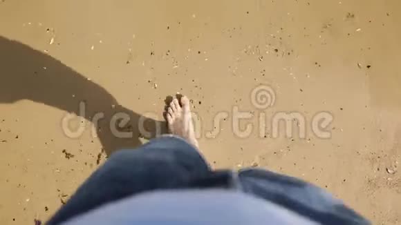 晒黑的雄性脚在海边的沙滩上高高的视野穿着牛仔裤光着脚在海滨散步的男人视频的预览图