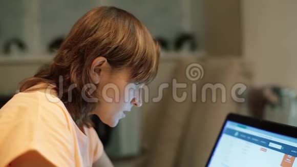 一个40岁的女人穿着睡衣坐在床上深夜背着笔记本电脑视频的预览图